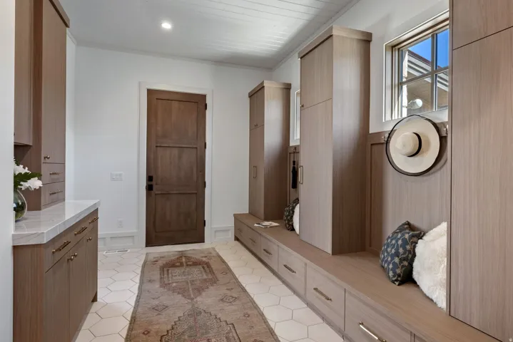 Built-in cabinetry with wood-finish, stone countertop, hexagon tile flooring, wood-paneled ceiling, and a paneled wood door