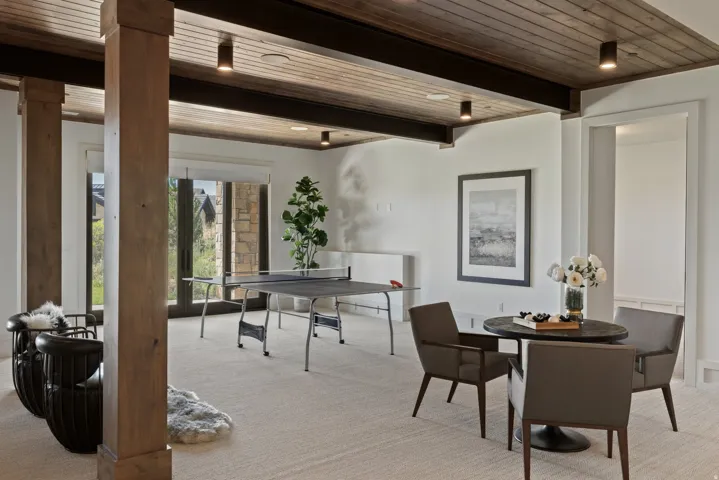 Wood-paneled ceiling with exposed beams, recessed lighting, and light-colored carpeting