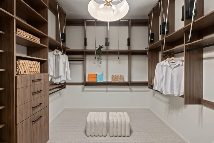 Custom closet system with extensive wood-finish shelving, integrated drawers with black hardware, and multiple hanging rods