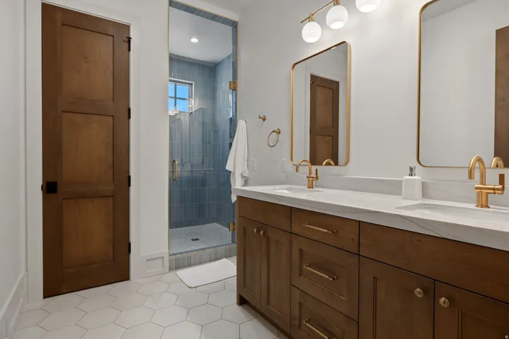 Dual vanity with gold-finish fixtures, white countertop, and wood-finish cabinetry