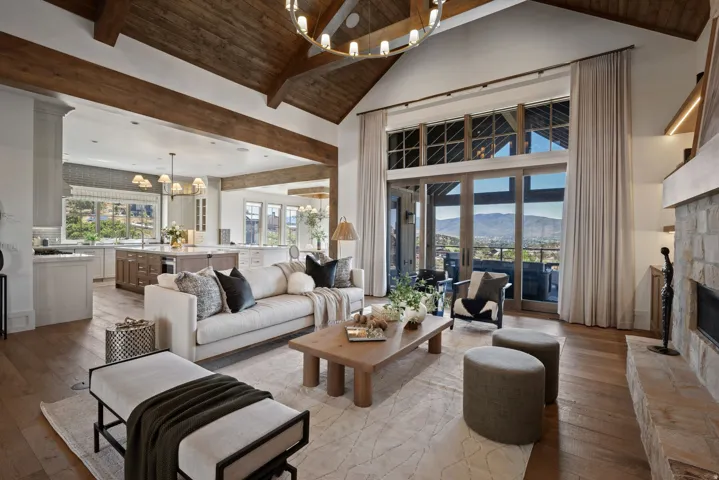 Vaulted wood-beamed ceilings, expansive sliding glass doors, and a stone-clad fireplace