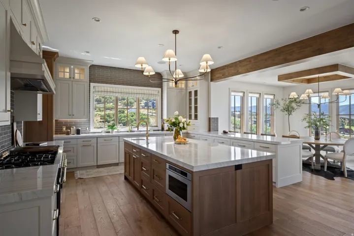 Kitchen featuring a large central island with integrated microwave, white cabinetry, a six-burner range, and wood-finish flooring