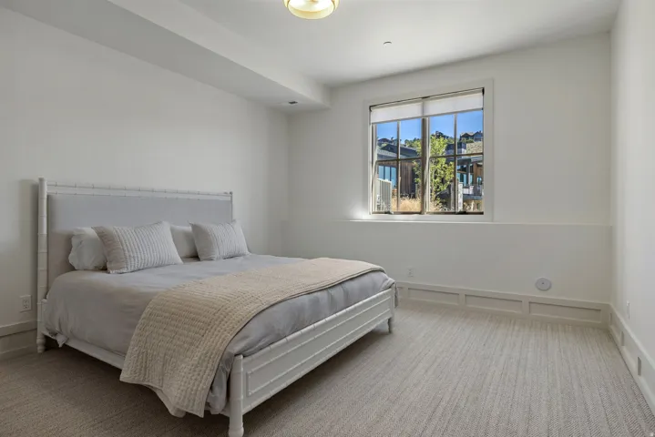Carpeted bedroom featuring a large window, integrated window blinds, recessed lighting, and white wall paneling