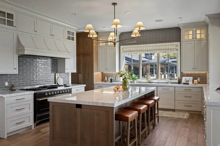 Gourmet kitchen with light-toned shaker cabinetry, subway tile backsplash, professional-grade range, and a spacious island with countertop seating