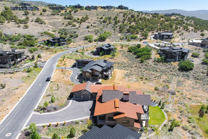 Hillside property featuring a multi-level design, a prominent orange-toned roof, and an attached garage with a paved driveway