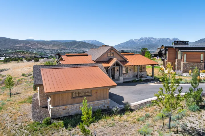 Exterior featuring copper-toned metal roofing, stone facade, wood siding, and an asphalt driveway