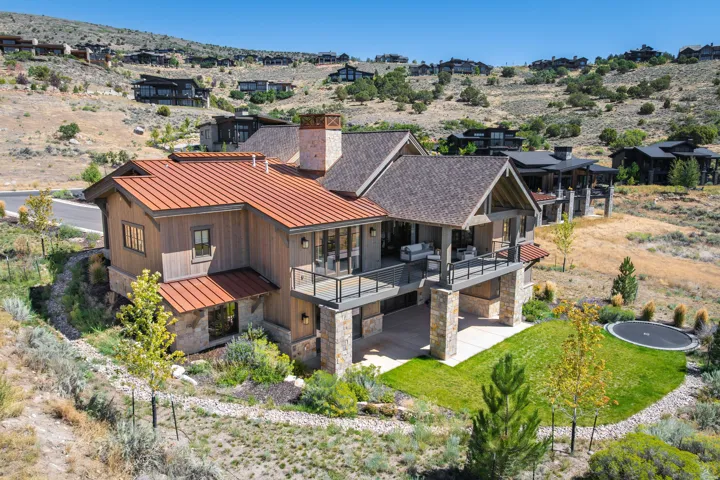 Multi-level home featuring a copper-tone metal roof, wood siding, and stone accents
