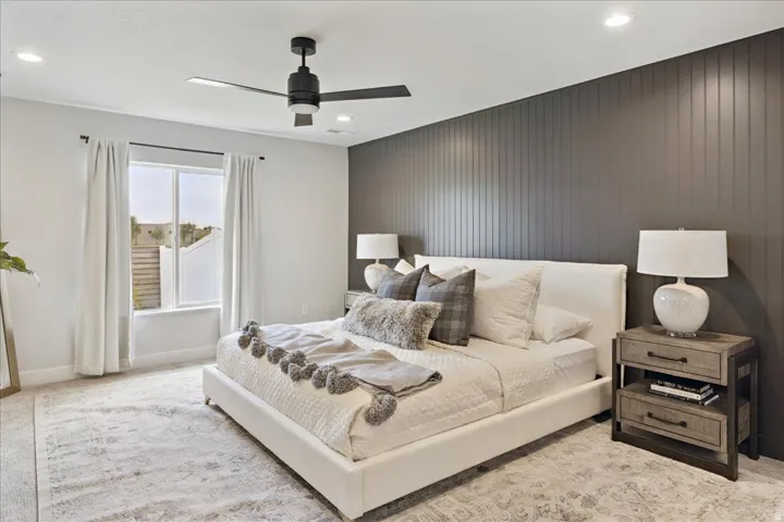 Recessed ceiling lighting, modern ceiling fan, accent wall with vertical paneling, large window with natural light, and plush carpeting