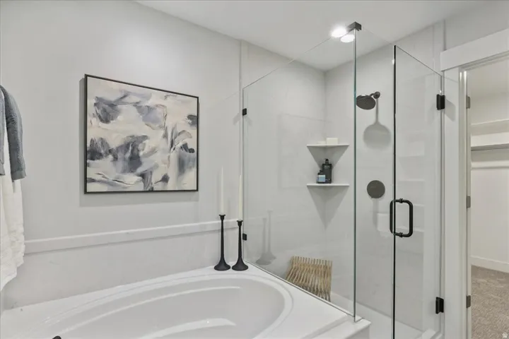 Built-in soaking tub with a tiled surround, glass-enclosed shower, wall-mounted showerhead, and matte black fixtures
