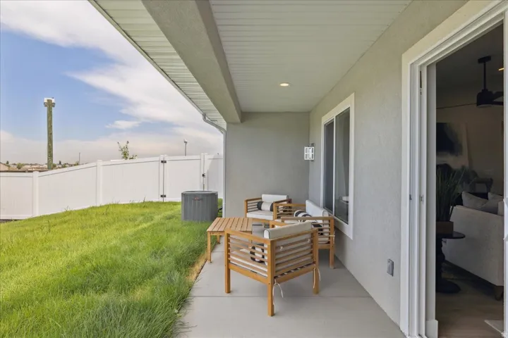 Covered patio with concrete flooring, sliding glass door entry, and an exterior wall light fixture