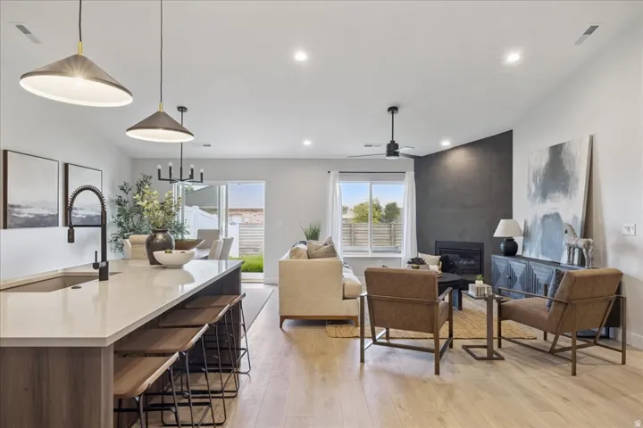 Open concept living space featuring wood-finish flooring, a kitchen island with seating, recessed lighting, and a fireplace with a dark accent wall