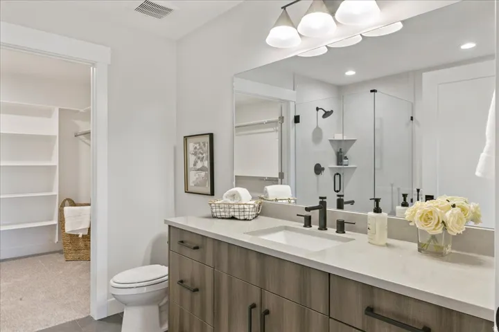 Wood-finish vanity with a light-toned countertop, a rectangular sink, and matte black fixtures