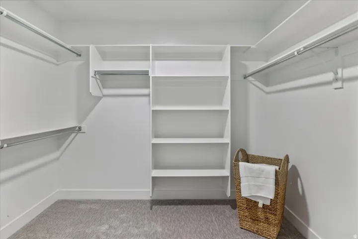 Built-in shelving, multiple hanging rods, and light gray carpeting