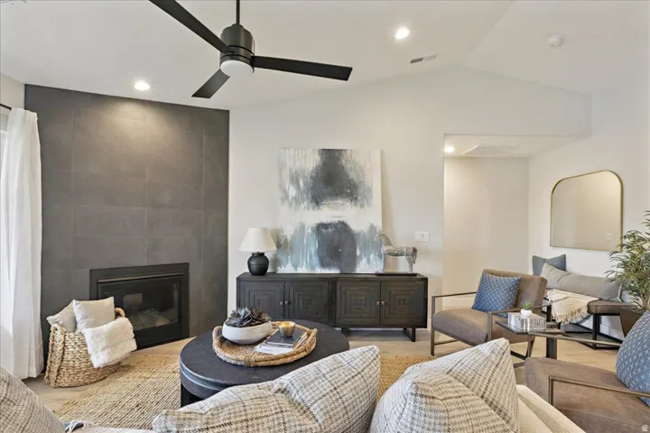 Vaulted ceiling with a contemporary black ceiling fan, recessed lighting, and a modern fireplace with a dark tile surround