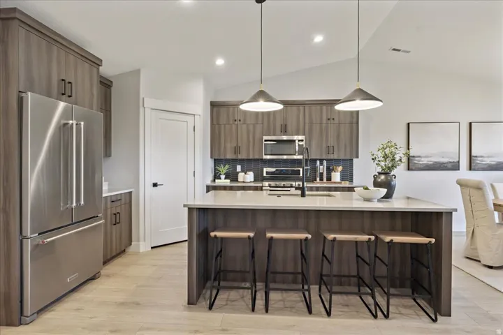 Kitchen featuring wood-finish cabinetry, stainless steel appliances, a center island with countertop seating, and pendant lighting