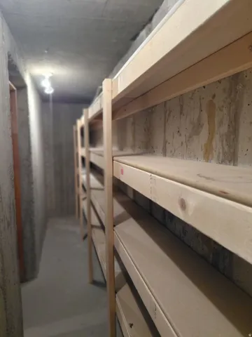 Spacious storage area featuring built-in wooden shelving and concrete walls