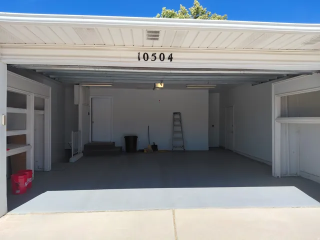 Two-car garage with a painted concrete floor, integrated overhead lighting, and white walls
