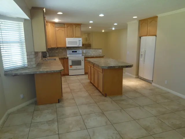 Kitchen with light wood cabinetry, stone-finish countertops, tile backsplash, and recessed lighting