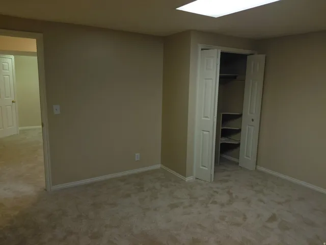 Neutral tone wall color, plush carpet flooring, bi-fold closet doors, built-in closet shelving, and recessed ceiling lighting