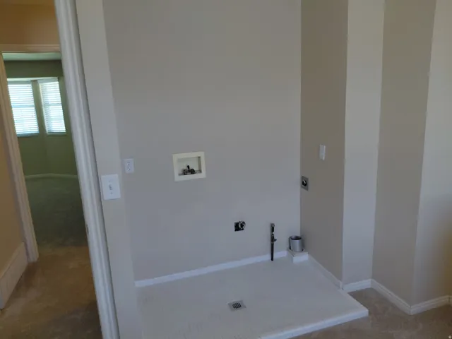 Utility area with tiled floor, wall hookups, and neutral painted walls