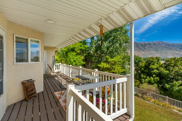 Covered outdoor deck with white railing, composite decking, and distant mountain scenery