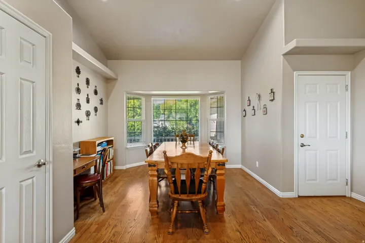 Hardwood-finish flooring, vaulted ceiling, bay window, white panel doors, and neutral wall tones
