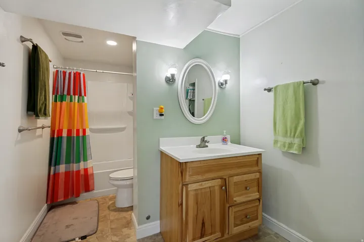 Bathroom featuring a wood-finish vanity with a white countertop and oval mirror