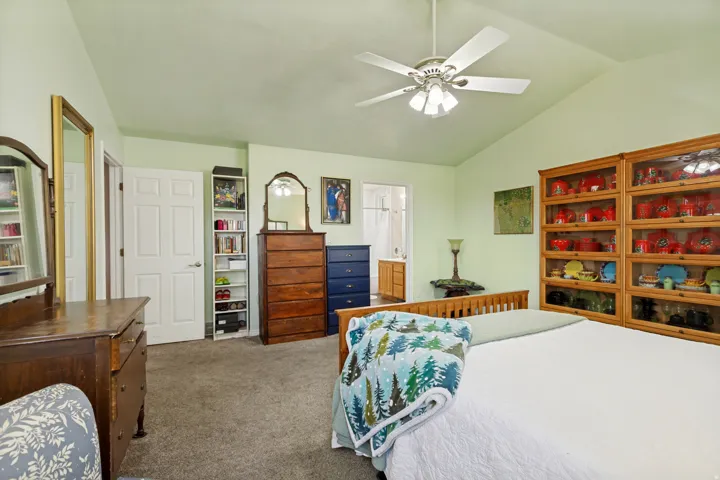 Vaulted ceiling with ceiling fan, built-in display cabinetry, and carpeted flooring