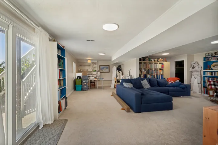 Recessed lighting, light-toned carpeting, built-in shelving, and sliding glass doors with direct outdoor access