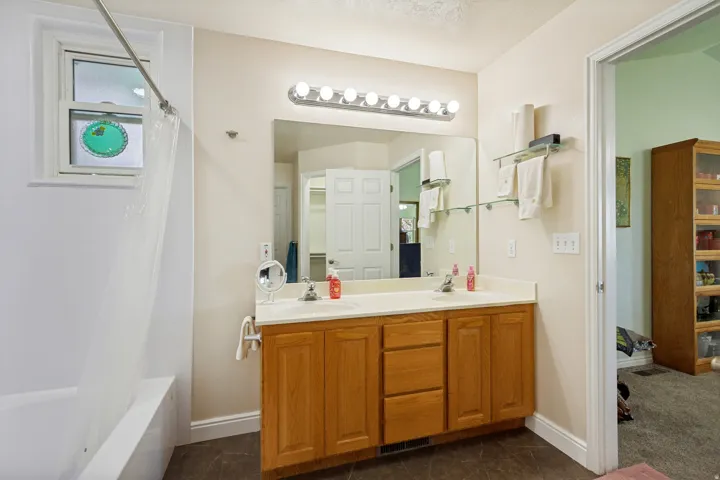 Double vanity with integrated sinks, wood-finish cabinetry, and overhead bar lighting