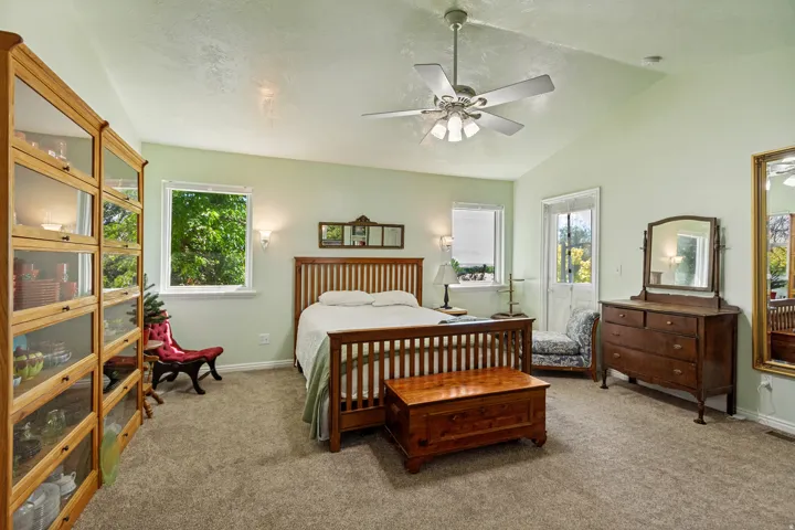 Vaulted ceiling with a ceiling fan, carpeted flooring, and a glass-paneled door