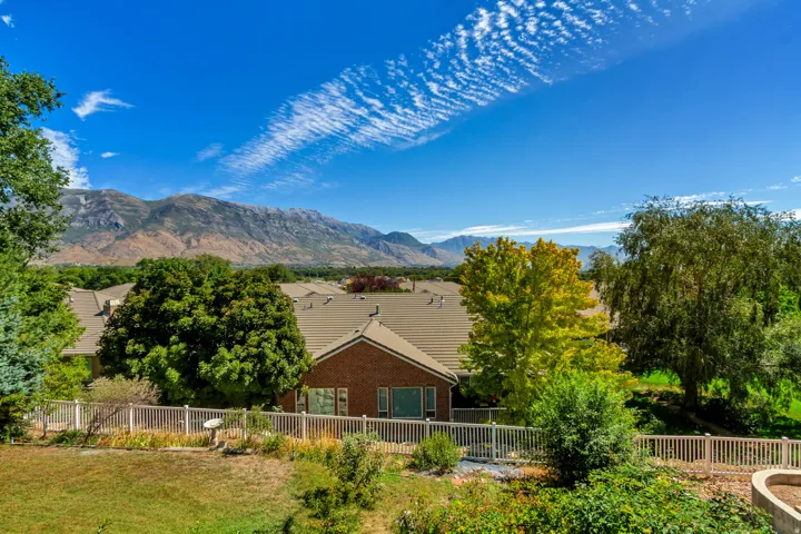 Mountain backdrop, mature trees, white picket fencing, brick exterior, tiled roofing