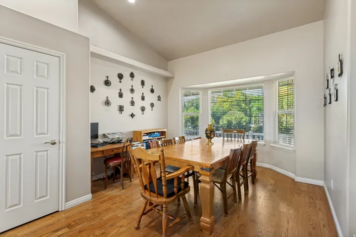 Vaulted ceiling, wood-finish flooring, and a large bay window