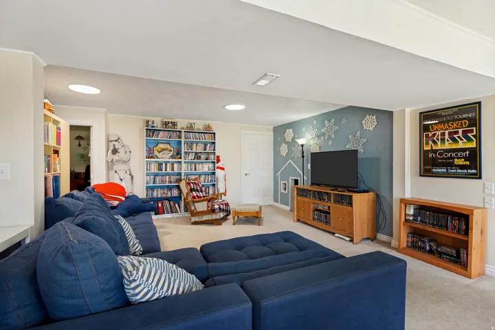 Recessed ceiling lighting, built-in shelving, light-colored carpeting, blue accent wall, and a wooden media console