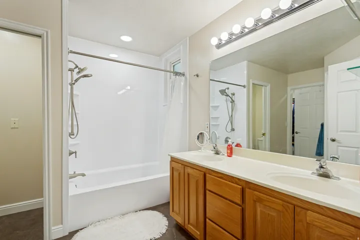 Double vanity with integrated sinks, wood-finish cabinetry, and an expansive mirror