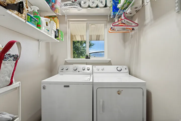 Dedicated laundry area featuring a window, built-in shelving, and white walls