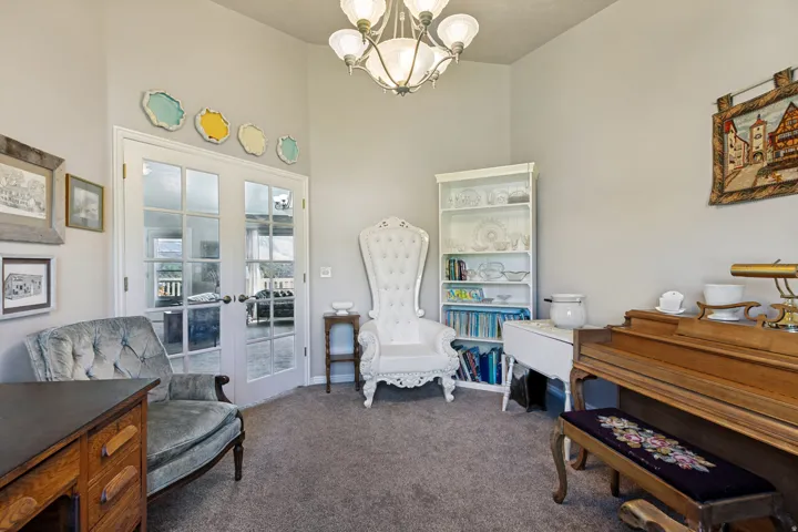 Vaulted ceiling with an attached chandelier, French doors, and built-in shelving