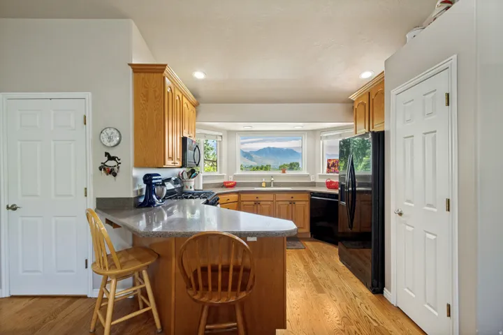 Kitchen featuring wood-finish flooring, recessed lighting, wood cabinetry, stone-finish countertops, and a bay window