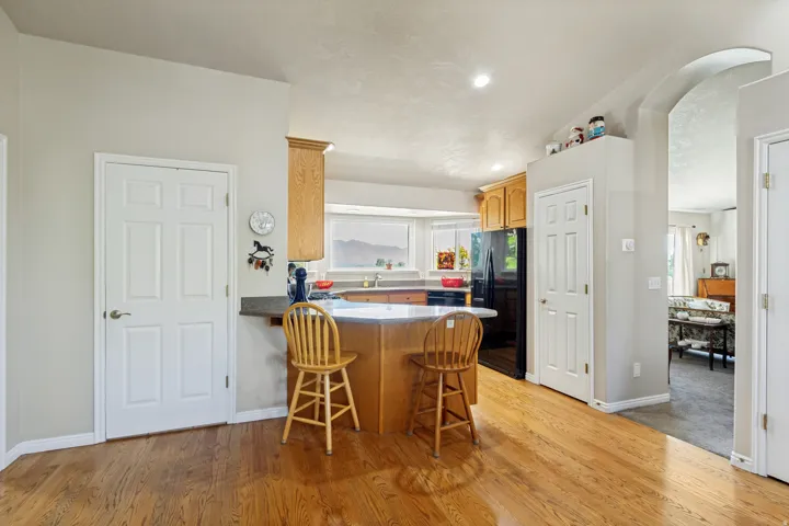 Hardwood-finish flooring, recessed lighting, wood cabinetry, built-in breakfast bar, and an arched entryway