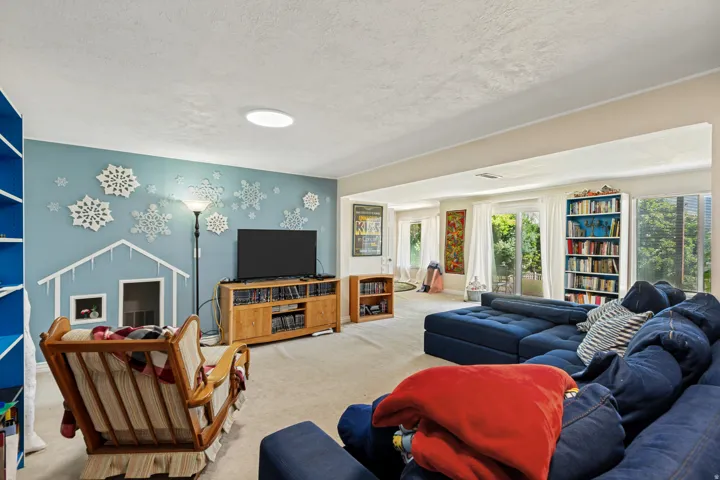 Carpeted living area with built-in shelving, recessed lighting, and expansive windows