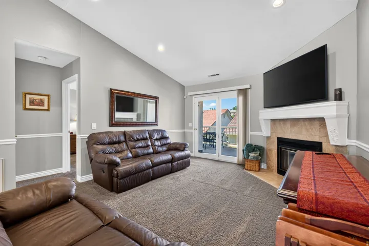 Vaulted ceiling, dual sliding glass doors, fireplace with mantel, and recessed lighting