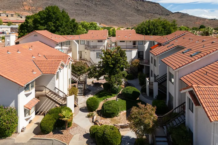 Terracotta tile roofs, white stucco exterior, multi-level structures, outdoor staircases, and mature landscaping