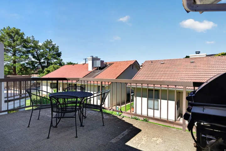 Concrete balcony with brown metal railing and surrounding residences featuring tile roofs