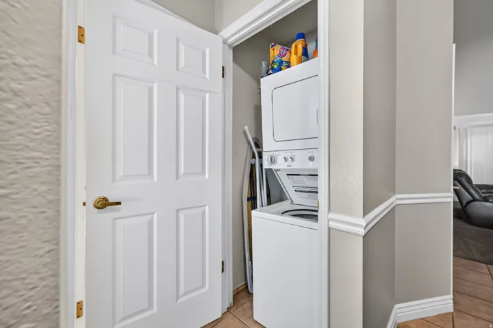 Laundry closet with stackable washer and dryer, finished with tile flooring