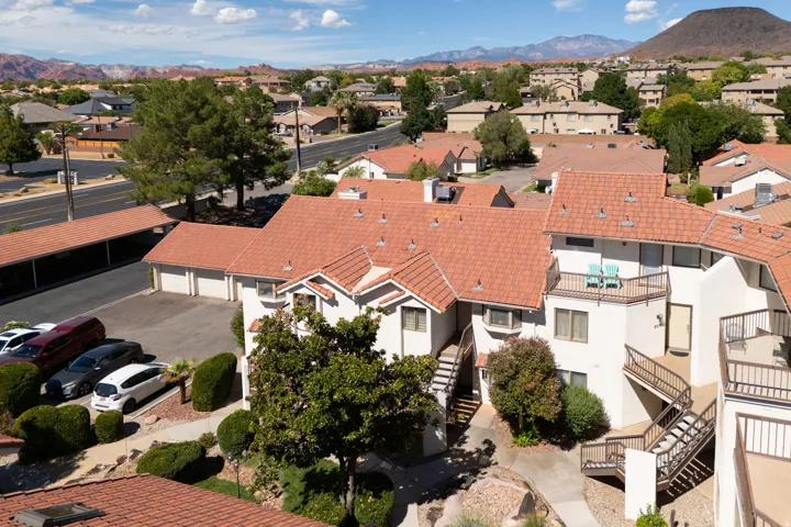 Terracotta tile roofing, balconies with metal railings, a covered parking structure, and an attached garage with multiple bays