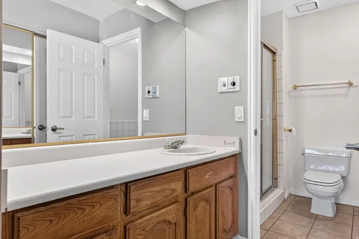 Vanity with wood-finish cabinetry, white countertop, and integrated sink