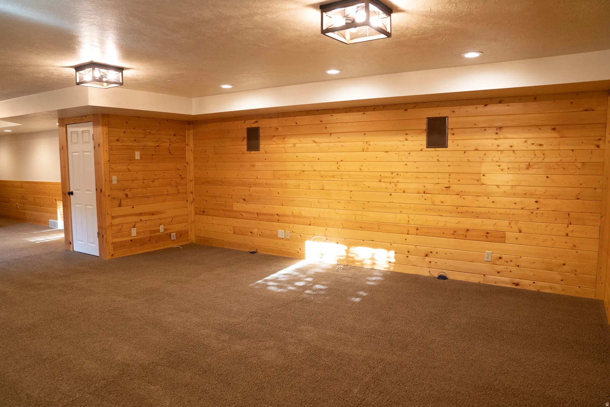 Wall paneling featuring natural wood finish, recessed ceiling lights, and two ceiling-mounted light fixtures