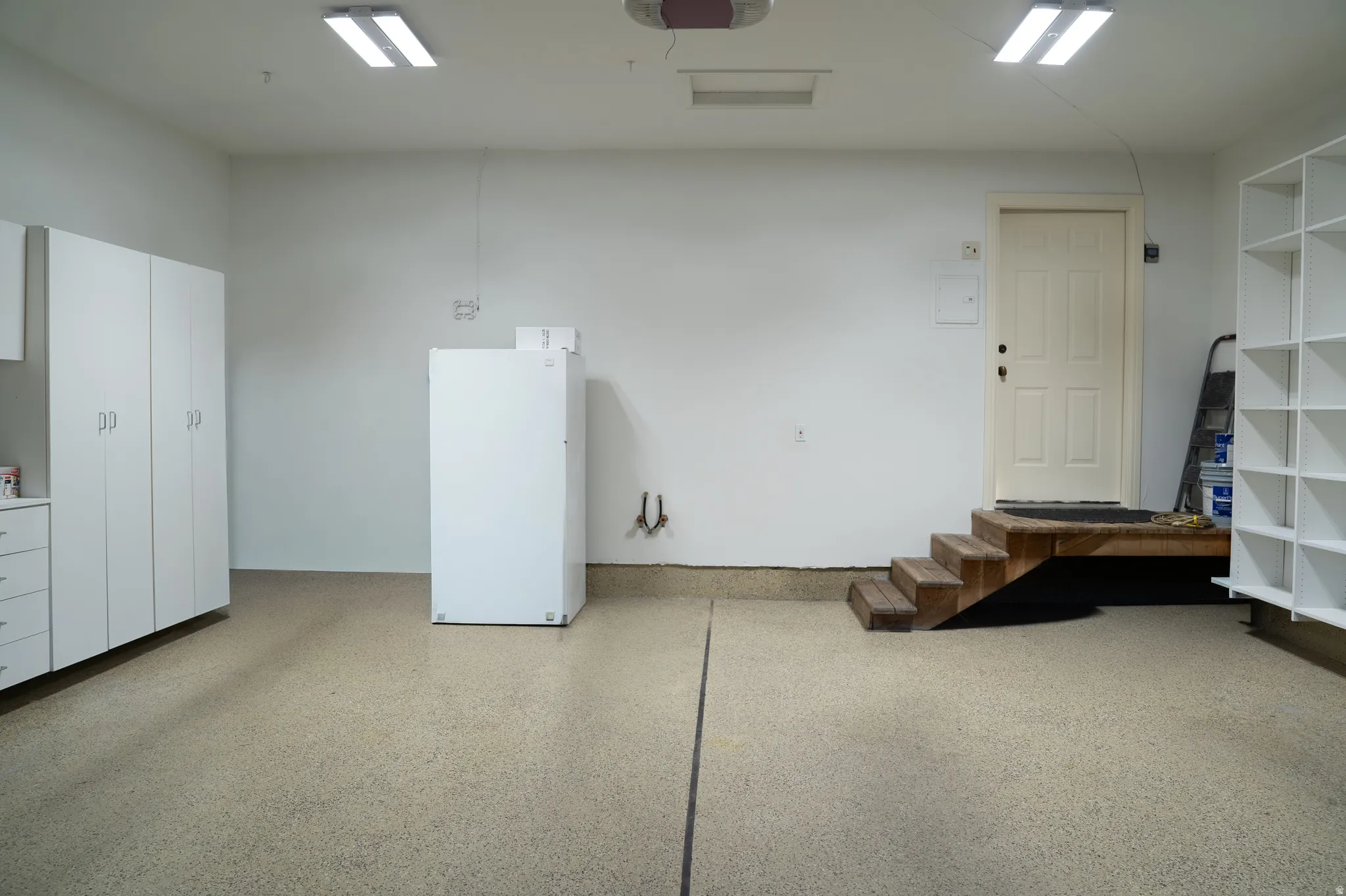 Epoxy-coated flooring, built-in storage cabinetry, fluorescent overhead lighting, and built-in shelving