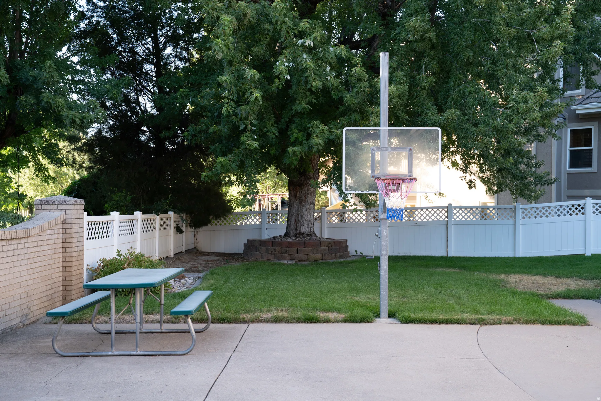 Concrete patio with brick wall, lawn area, and privacy fencing