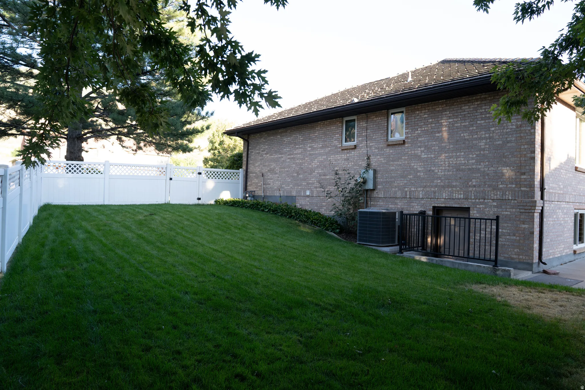 Expansive lawn with a white lattice-top fence and gate